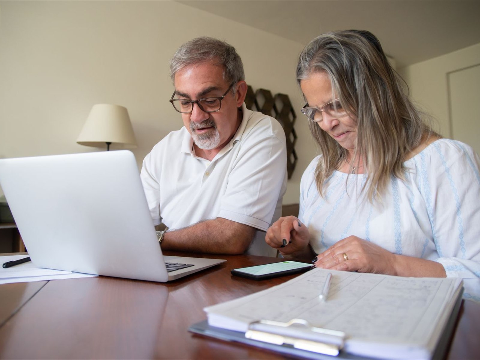 A retired couple reviewing their prescription paperwork together at home