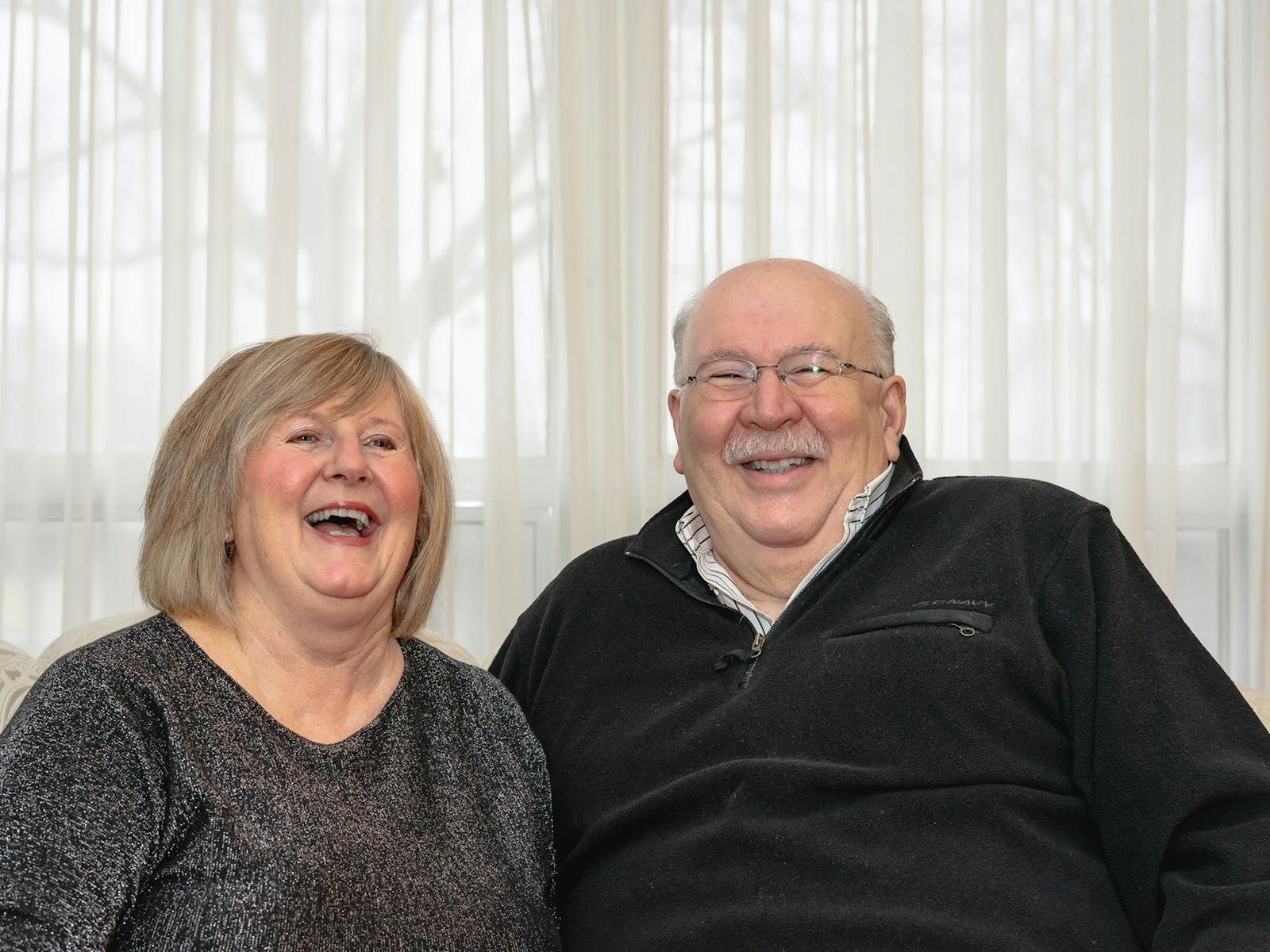 A couple smiling together while reviewing their Medicare plan options at home
